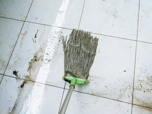 A mop removing dirt stains from white tile, demonstrating safe cleaning techniques.